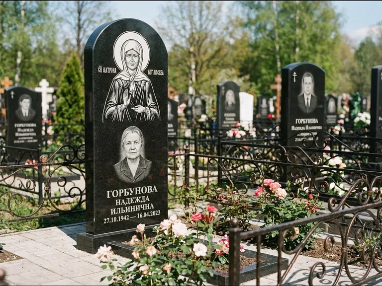 Памятник с гравировкой иконы: стела с арочным верхом и киотом под образ — гравировка образа Матроны Московской, гранитный цоколь с тёмной плиткой, работа «Ковалёв» в Новокузнецке
