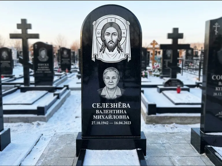 Памятник с гравировкой иконы: небольшая скромная одиночная стела с именной иконой — золочёный нимб на образе, аккуратный участок с газоном, работа «Ковалёв» в Новокузнецке