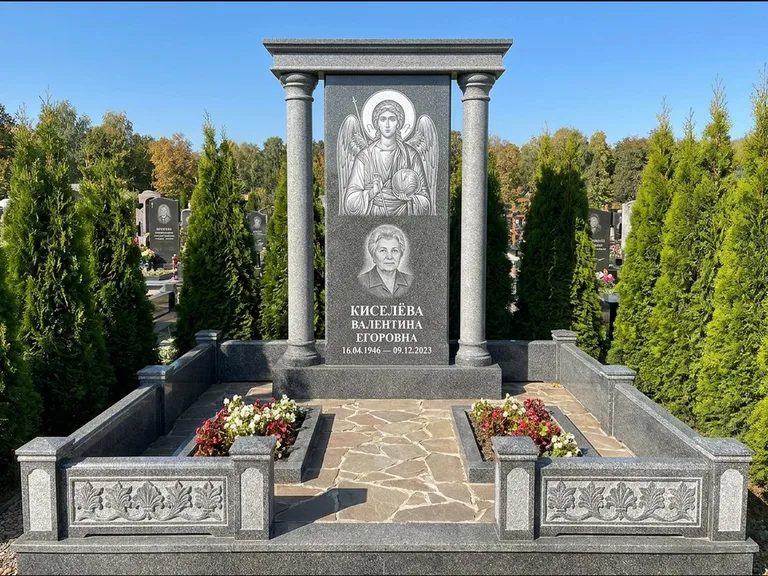 Памятник с гравировкой иконы: массивная стела с двускатным навершием-домиком — гравировка Николая Чудотворца, живая изгородь из туи, работа «Журавлёв» в Новокузнецке