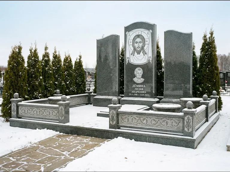 Памятник с гравировкой иконы: узкая вертикальная стела-пилон с ликом — икона в резной рамке-киоте, открытая лужайка без ограды, работа «Одинцов» в Новокузнецке