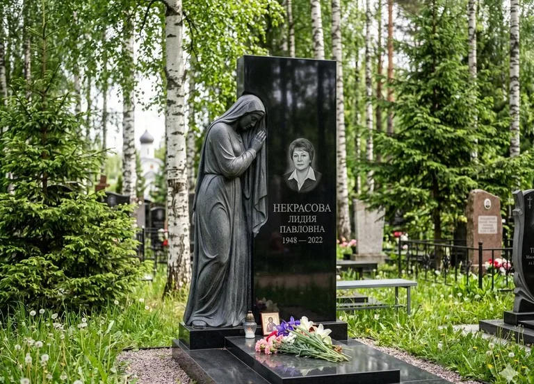 Гранитная фигура скорбящего мужчины у чёрной стелы в Новокузнецке